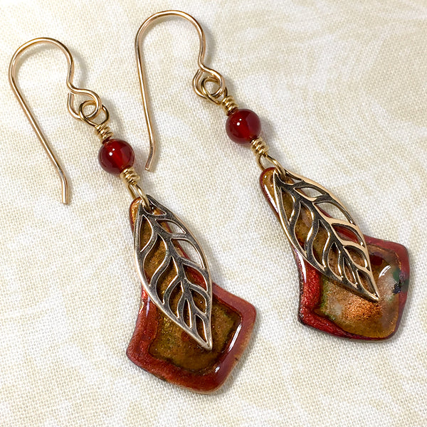 Earrings with bronze leaves, copper and russet enameled copper charms, and carnelian beads